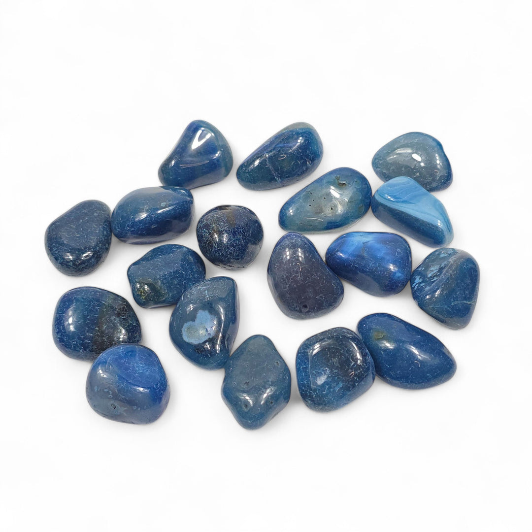 Agate bleue teintée roulée, pierre d’expression reliée au chakra de la Gorge, aux nuances bleues apaisantes et lumineuses.