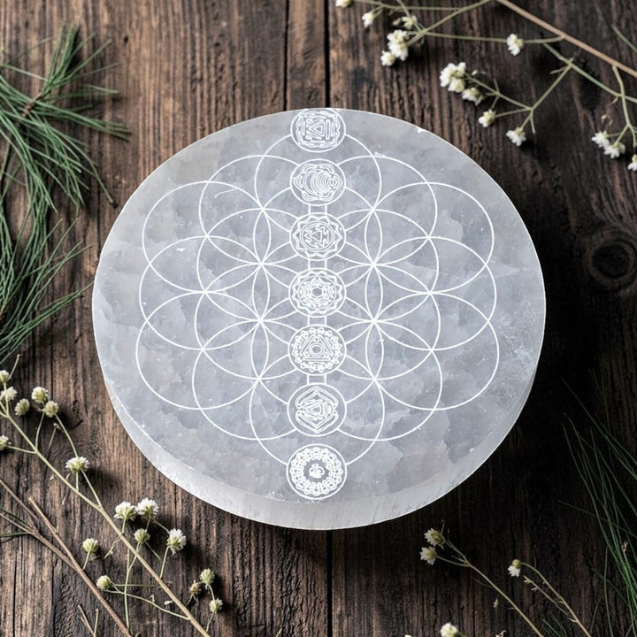 Assiette ronde en sélénite naturelle de 10 cm ornée de la Fleur de Vie et de symboles chakras.
