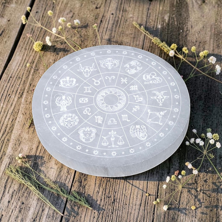 Assiette ronde en sélénite avec symbole astrologique gravé et finition polie. grandeur de 12 à 14 cm.
