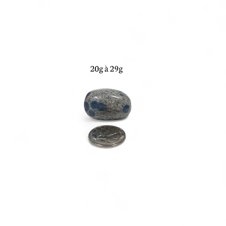 K2 roulée pesant entre 20g et 29g, photographiée à côté d’une pièce de 25 cents pour indiquer la taille réelle.