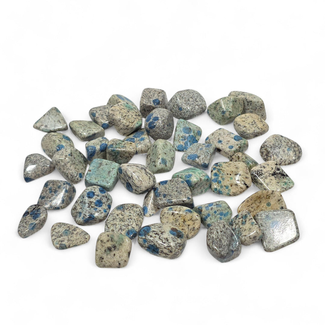 K2 roulée, pierre d’équilibre et de communication associée aux chakras de la gorge, du troisième œil et du plexus solaire, aux teintes grises mouchetées de bleu azurite.